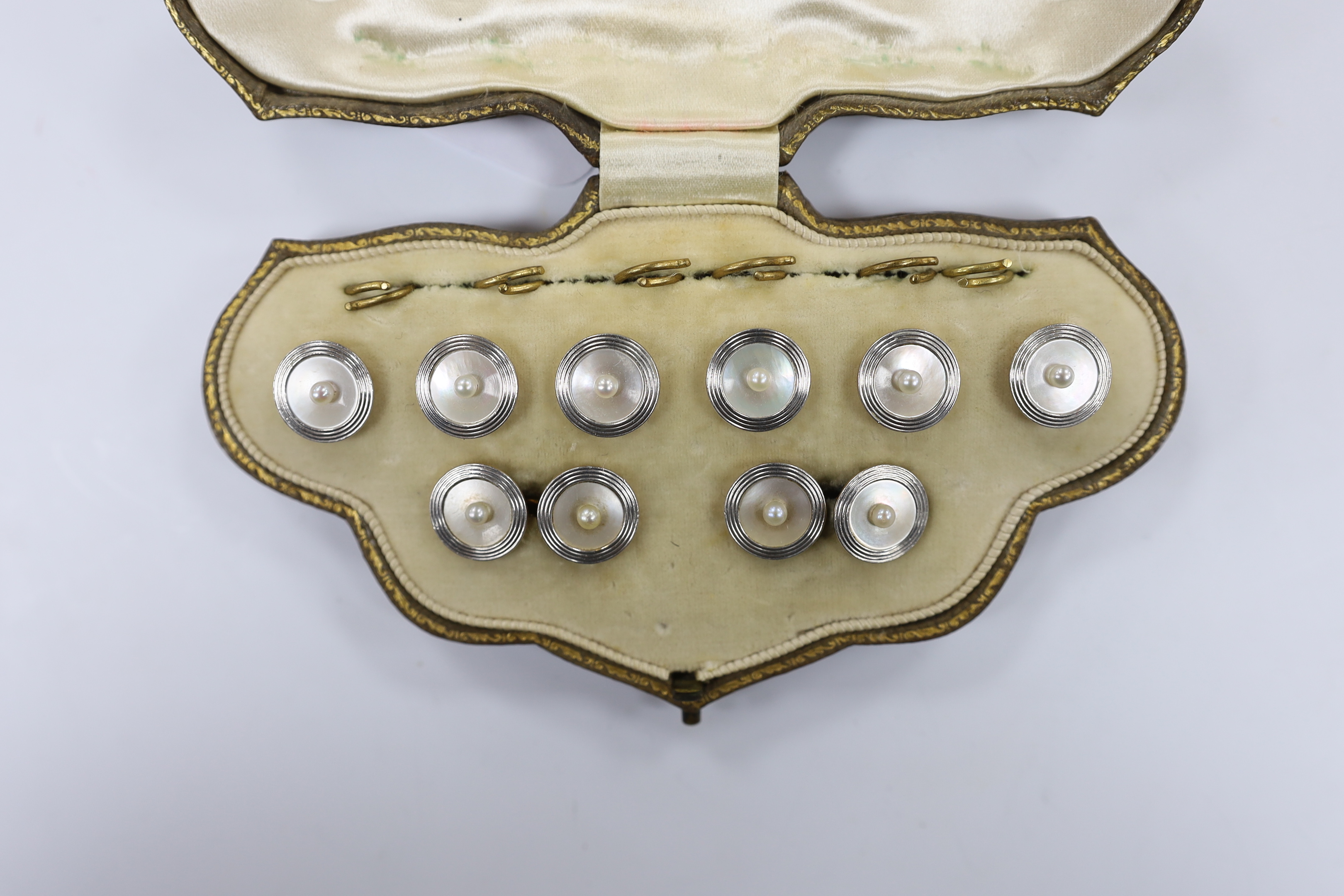 An early to mid 20th century 18ct, mother of pearl and seed pearl set eight piece dress stud set, including pair of cufflinks and six buttons, in fitted gilt tooled leather box by Mappin Brothers, gross weight 17.4 grams